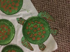 three paper plates with turtles on them sitting on top of a carpeted floor next to a white towel