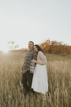 a man and woman standing in tall grass