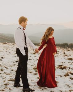 a man and woman in formal wear holding hands on top of a snow covered hill