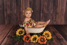 a baby sitting in a tub surrounded by sunflowers