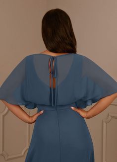 a woman in a blue dress with her back to the camera and hands on her hips