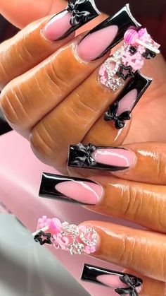 a woman's hand with pink and black nail polishes on her nails, decorated with flowers