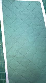 a green quilted blanket laying on top of a cutting board next to a pair of scissors