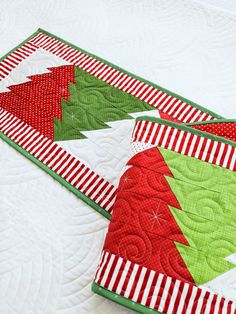 two red and green christmas quilts sitting on top of each other