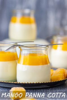 three glass jars filled with pudding on top of a black plate next to small pieces of fruit