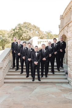 a group of men in black suits standing on some steps with their arms around each other