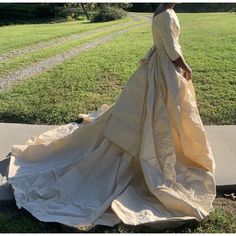 a woman in a long dress is walking down the street with her hand on her hip