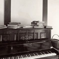 an old piano is sitting in front of a mirror and books on top of it