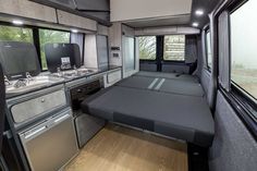 the interior of a camper with two beds and stove top ovens in it