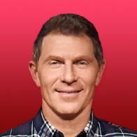 a man in plaid shirt and tie smiling at the camera with red background behind him