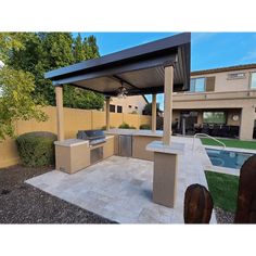 an outdoor kitchen area with grill, sink and pool in the back yard at home