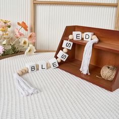 a wooden shelf with blocks spelling the word bleash on it and some flowers