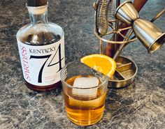 a bottle of kentucky 47 and a glass with an orange slice on the rim next to it