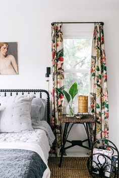 a bed room with a neatly made bed next to a window and a painting on the wall