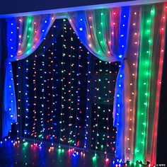 a room with lights on the walls and curtains around it, all lit up in different colors