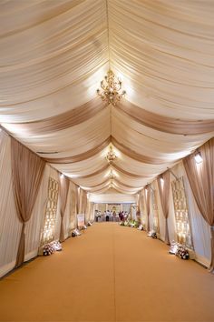 the inside of a wedding tent with white drapes and chandeliers