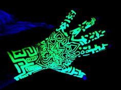 glow in the dark gloves with designs on them are glowing green and blue, as well as black background