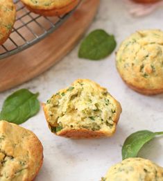 small muffins with spinach and cheese on a cooling rack next to some leaves