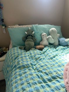 three stuffed animals sitting on top of a bed next to pillows and blankets in a bedroom