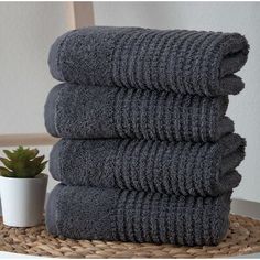 a stack of towels sitting on top of a table next to a potted plant