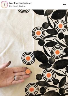 a woman's hand on top of a black and white cloth with orange circles