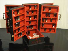 two red shelves filled with bottles on top of a black table next to each other