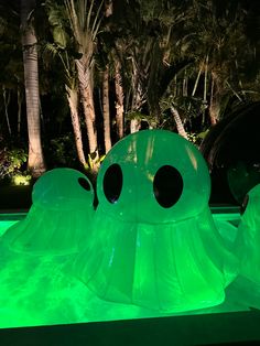 an inflatable octopus float is lit up at night with palm trees behind it