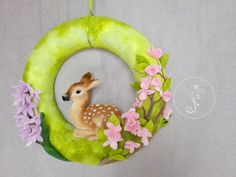 a deer ornament hanging from a green wreath with pink and purple flowers on it