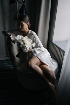 a woman sitting on a chair with flowers in her hand