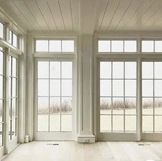 an empty room with large windows and wooden flooring on the side of the wall