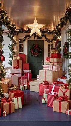 christmas presents are stacked on the front porch with garlands and wreaths around them