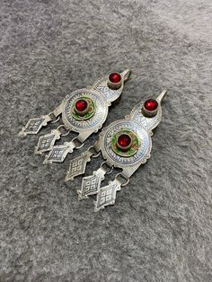 Gorgeous vintage earrings of headdress adornments worn by berber women,made by tiznit jewelers (South of morocco). Decorated with niello,green and yellow enamels and red Glass. To make a niello decoration the jeweler engraves the metal ,spreads the niello a black melted alloy and polishes the surface . Length : 10,7cm Width : 4cm Total weight : 56,2g Ornate Pendant Earrings For Ceremonial Occasions, Traditional Silver Chandelier Earrings For Ceremonial Occasions, Antique Handmade Earrings For Ceremonial Occasions, Traditional Festival Chandelier Earrings With Intricate Design, Traditional Ceremonial Earrings For Pierced Ears, Traditional Pendant Earrings With Intricate Design, Traditional Handmade Earrings For Ceremonial Use, Traditional Handmade Earrings For Ceremonial Occasions, Traditional Pierced Chandelier Earrings For Festivals