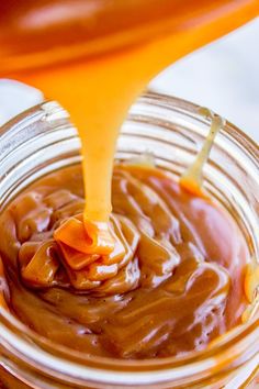 a spoon pouring caramel sauce into a jar