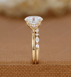 a close up view of a gold ring with an oval cut diamond on the side