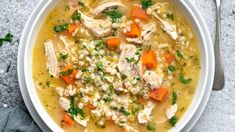 a bowl of chicken and barley soup with carrots, parsley on the side