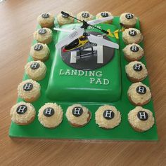 a green cake with cupcakes and a helicopter on it