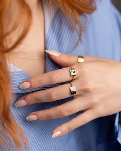 a woman with red hair wearing two different rings on her finger and one ring is gold