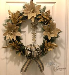 a christmas wreath with gold poinsettis and silver ribbon hanging on a door