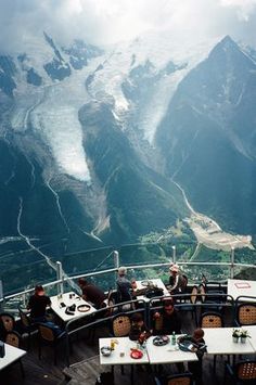 an image of some people sitting at a table in the mountains with snow on them