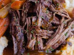 a close up of food on a plate with mashed potatoes and meat in gravy