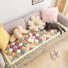 a cat is laying on a patchwork couch with pillows and stuffed animals next to it