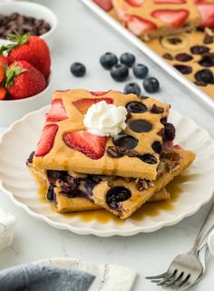 two pieces of blueberry waffles on a plate with strawberries and chocolate chips