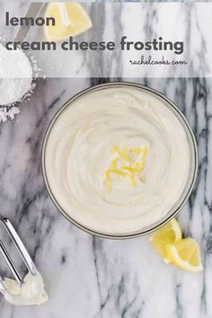 lemon cream cheese frosting in a glass bowl on a marble counter with two spoons