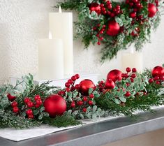 christmas decorations with candles and greenery on a mantle