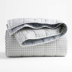 an unmade bed with grey and white checkered sheets