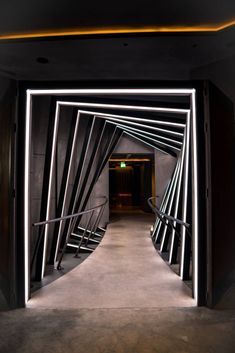 an open door leading to a hallway with stairs and railings in the center, illuminated by neon lights