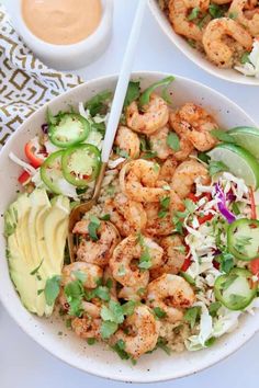 two bowls filled with shrimp and vegetables next to dipping sauce