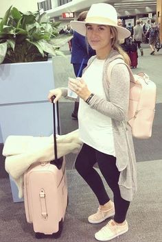 a woman is carrying her luggage at the airport with it's wheels down and smiling