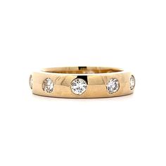 a yellow gold ring with five diamonds on the inside and outside, set against a white background