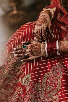 a woman in red and gold dress holding her hands up to show the hendi